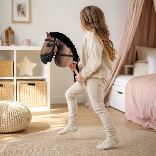 Mädchen beim Hobby Horsing mit braunem Steckenpferd im Kinderzimmer